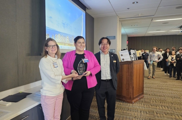 Photo of Kapil holding her award flanked by two faculty members